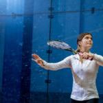 Trinity college squash player serving the ball with racket